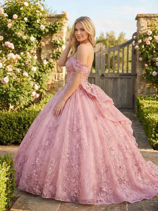 Woman in a pink embroidered ball gown with cold-shoulder sleeves standing in a garden